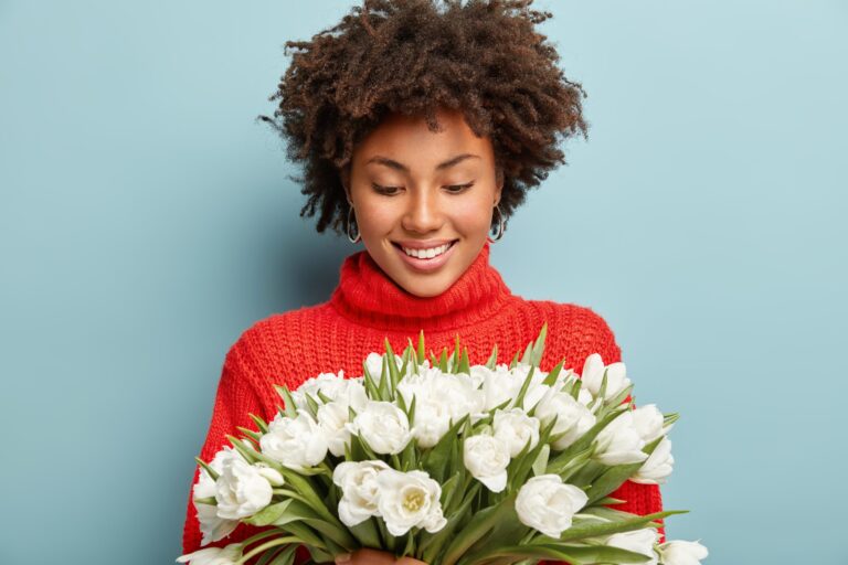 modelo feminino de aparencia agradavel e satisfeita com cabelo encaracolado fica feliz com flores brancas da primavera scaled 1