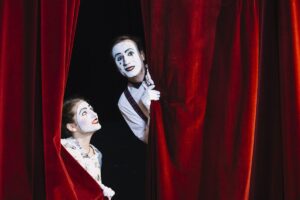 sorrindo artista feminino mime olhando artista mime masculino a espreitar da cortina scaled e1680043996900