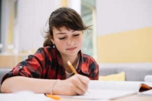 teen girl writing in textbook scaled e1679960731333