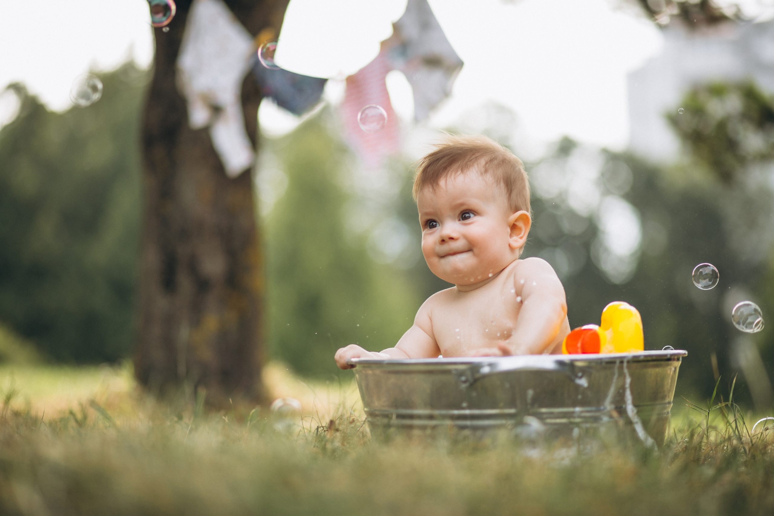 Bebê dentro de recipiente de água olhando para bolinhas de sabão
