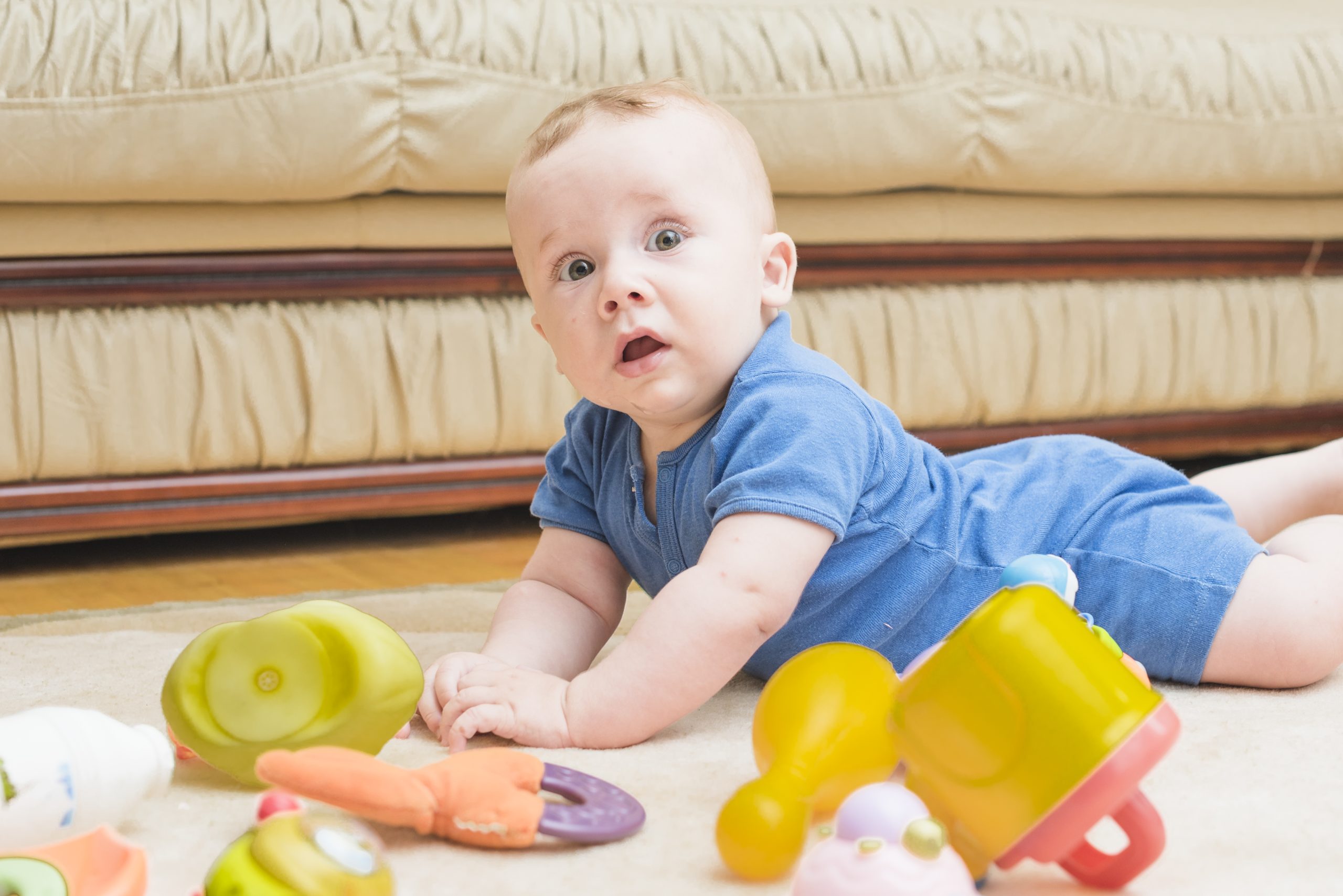 bebê brinca no chão bruços em meio a seus brinquedos