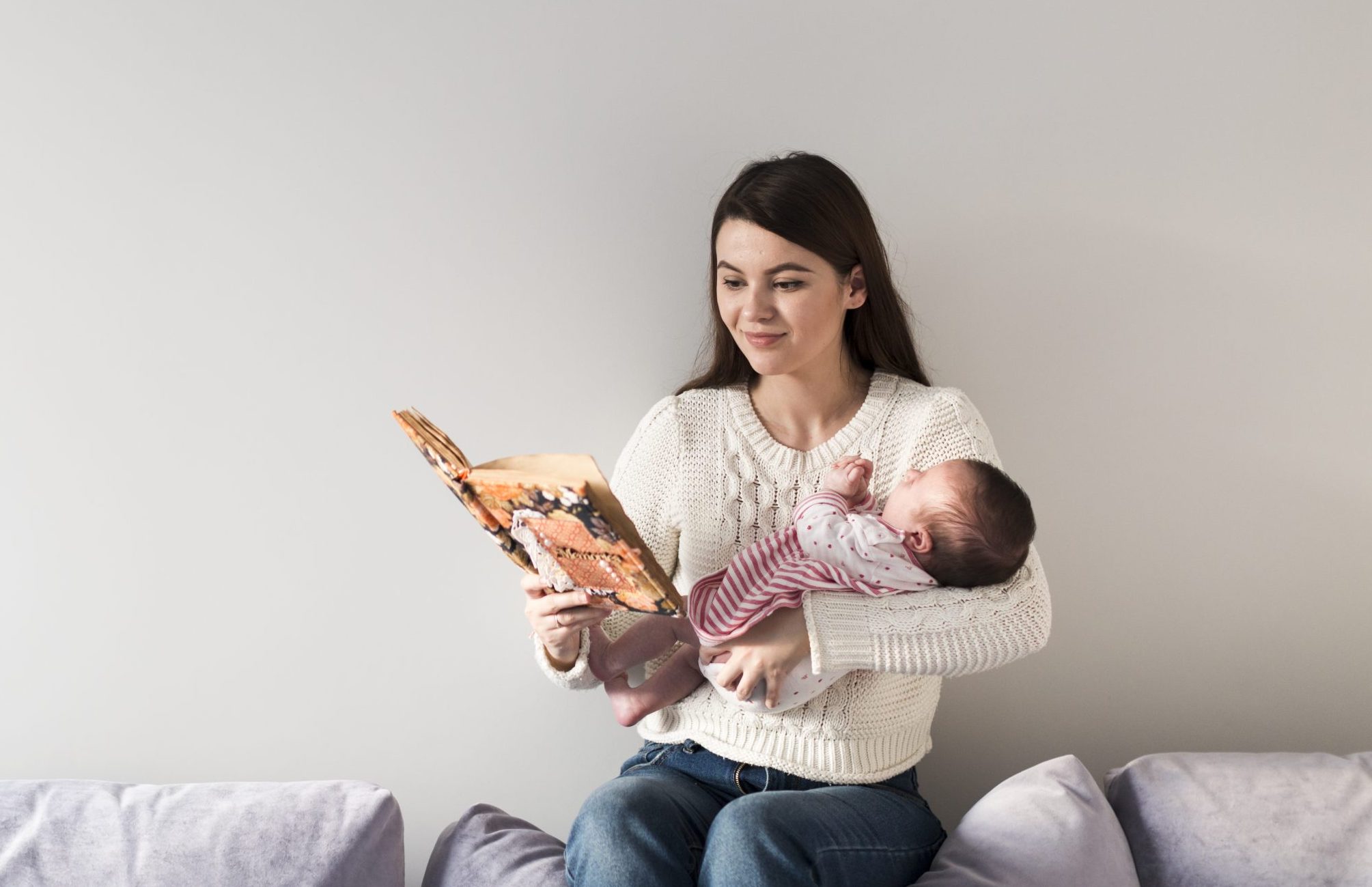 mulher lê uma história infantil em um livro para um bebê em seu colo