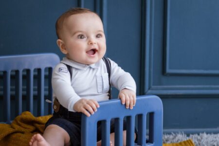 Atividades para Bebê de 9 meses: Atividades para aprender brincando! garoto feliz e sorridente com roupas aconchegantes no quarto scaled e1689003410285