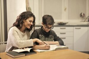Atividades Sobre o Dia das Mães 2024: PDF para Imprimir Uma mãe ajudando o seu filho a fazer a tarefa da escola