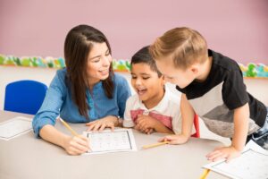 professor de pre escola de boa aparencia e alunos se divertindo aprendendo na sala de aula scaled e1692906977417