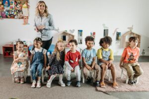 Uma professora em pé atrás de 6 alunos [crianças na escola]