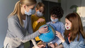 Atividades Sobre o Dia do Meio Ambiente 2024: PDF para Imprimir Professora ensinando crianças sobre o meio ambiente e o planeta