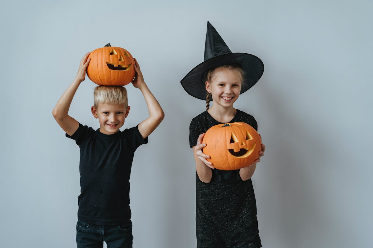 Duas crianças seguram uma abóbora de decoração para Halloween