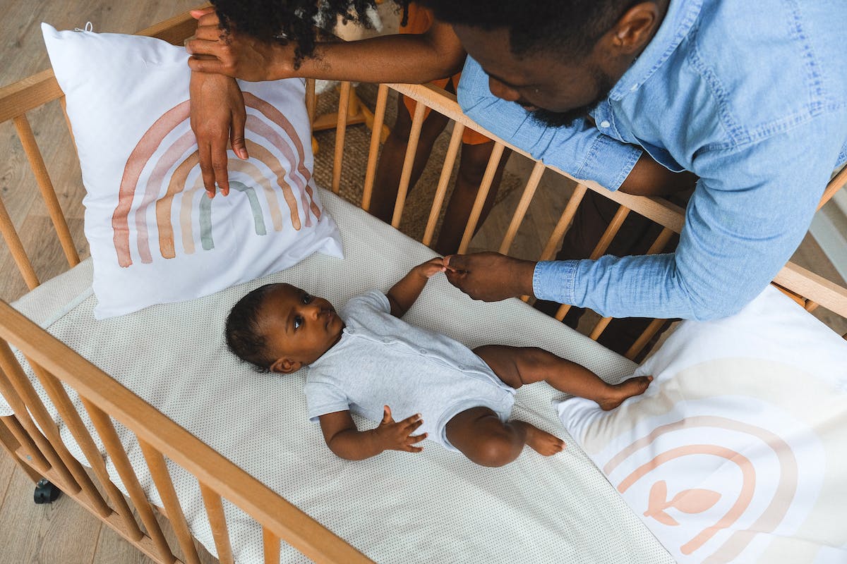 Um bebê está no berço. Seus pais estão vendo como ensinar o bebê a dormir sozinho