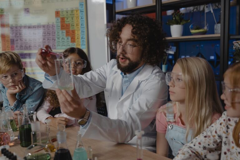 Professor dequímica faz experimento com alguns alunos que o acompanham sentados ao seu lado