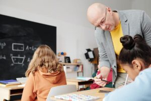 Um professor na frente do quadro mostrando a atividade de matemática para os alunos