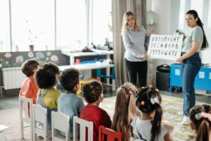 Duas professoras na frente do quadro mostrando a atividade de folclore para os alunos