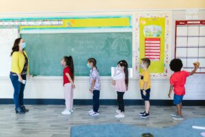 Professora na frente da sala de aula brincando com sua turma de crianças
