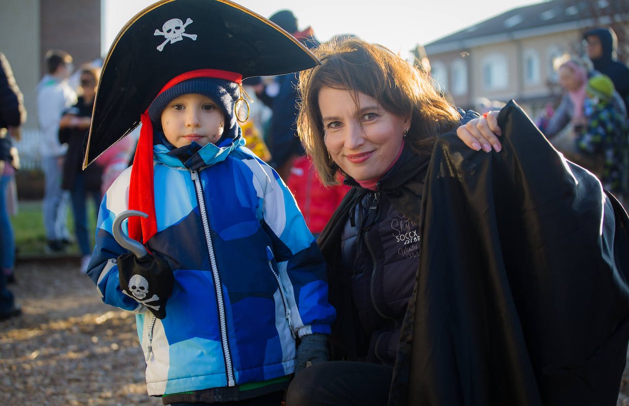 Uma mãe está agachada ao lado do seu filho que está fantasiado de pirata