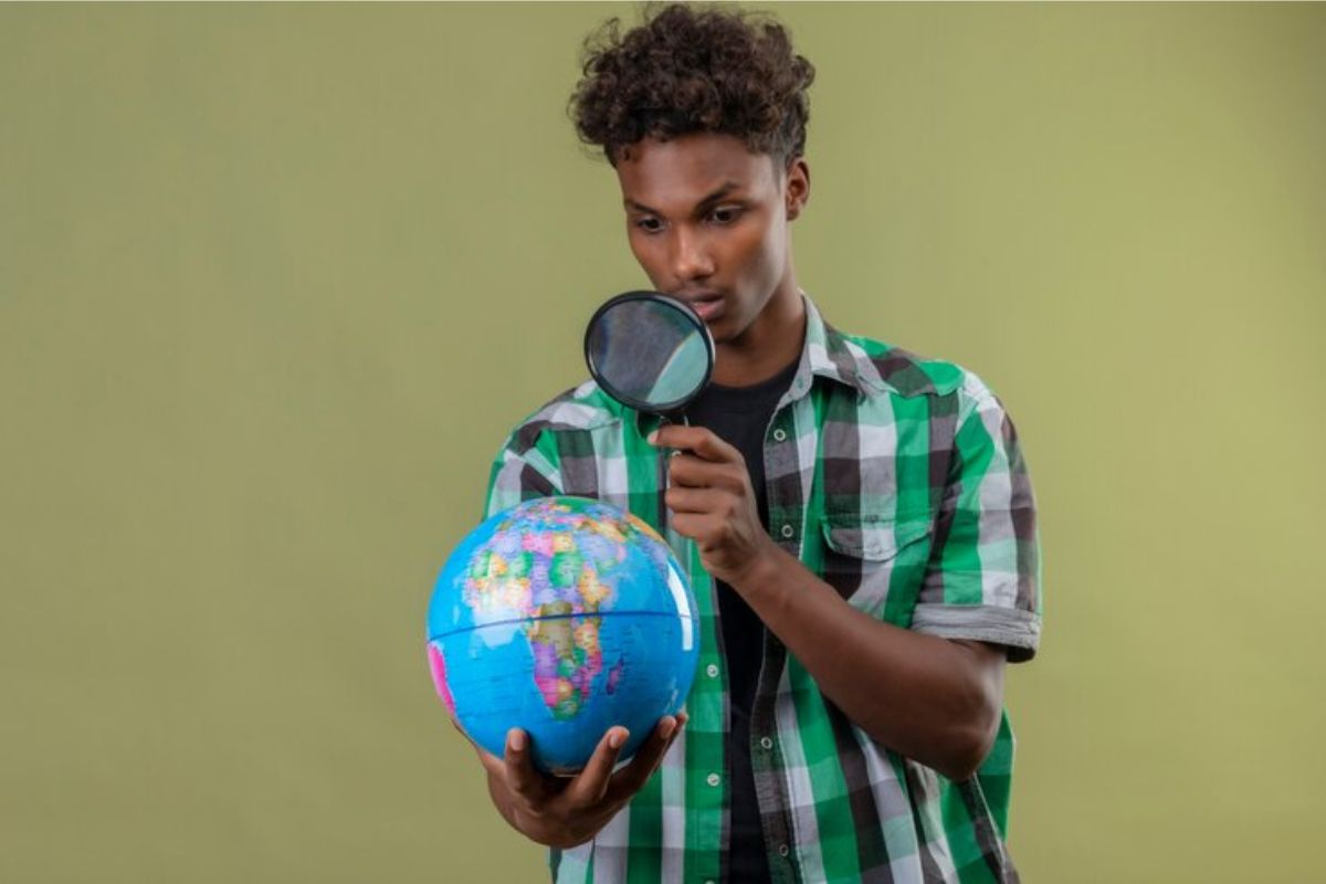 Um aluno está segurando uma luoa enquanto olha para um globo terrestre