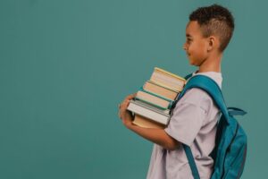Um aluno está segurando alguns livros empilhados em seu braço