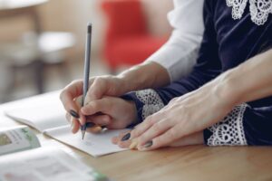 Atividade Letra M para Educação Infantil: Modelos Didáticos A mão de uma professora auxiliando a aluna a escrever