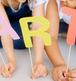 Imagem de três crianças, cada uma segura uma letra em um palito e formam a palavra ART