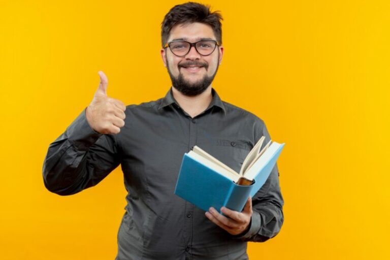 Um professor está com o livro na mão e faz sinal de positivo