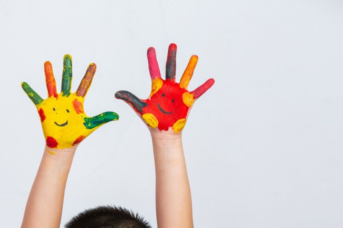 Aparecem as mãos pintadas de uma criança na escola