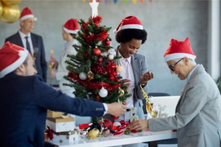 Um grupo de professores está reunido em uma sala enquanto enfeitam uma árvore de natal