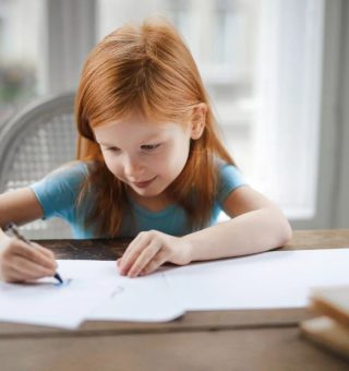 Uma pequena aluna escreve em seu caderno