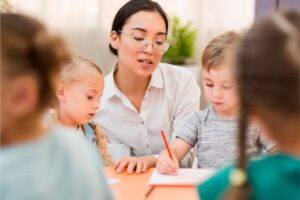 Uma professora está auxiliando um aluno que escreve no caderno