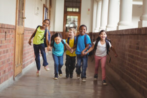 Datas comemorativas: planeje atividades escolares com propósito! crianças de 5 a 7 anos em ambiente escolar correndo de mãos dadas sorrindo