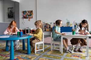 Crianças sentadas em mesas na sala de aula, concentradas em atividades de escrita e desenho, em um ambiente escolar colorido e organizado, representando um ditado de palavras 5º ano difícil aplicado em contexto educativo.